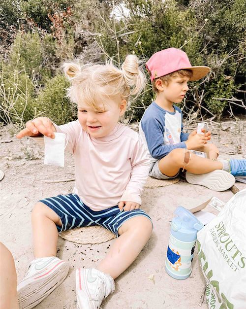Child filling a tea bag with tea leaves, building fine motor skills and sensory awareness at Oak Riparian Park in Oceanside.