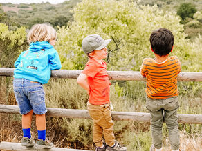 Three boys climbing a fence and looking out over Lake Calavera, building confidence and social-emotional bonds in nature.