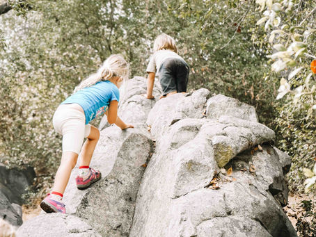 Children climbing rocks together at Oak Riparian Park in Carlsbad, building strength and confidence through supervised risky play.
